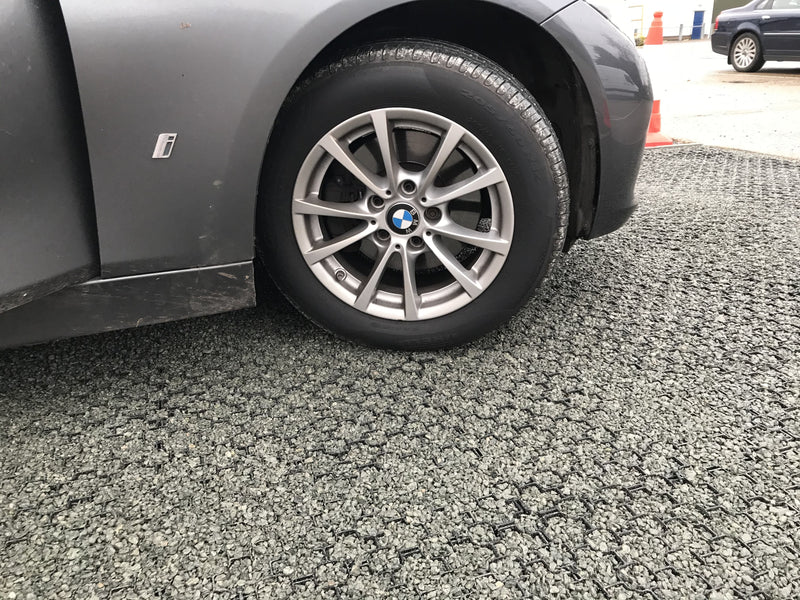 Load image into Gallery viewer, A BMW car wheel can be seen on a carpark surface created using Terram Bodpave 40 and gravel.